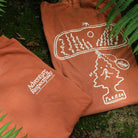 Adventure respectfully front and back of  t shirt shown folded on a mossy surface