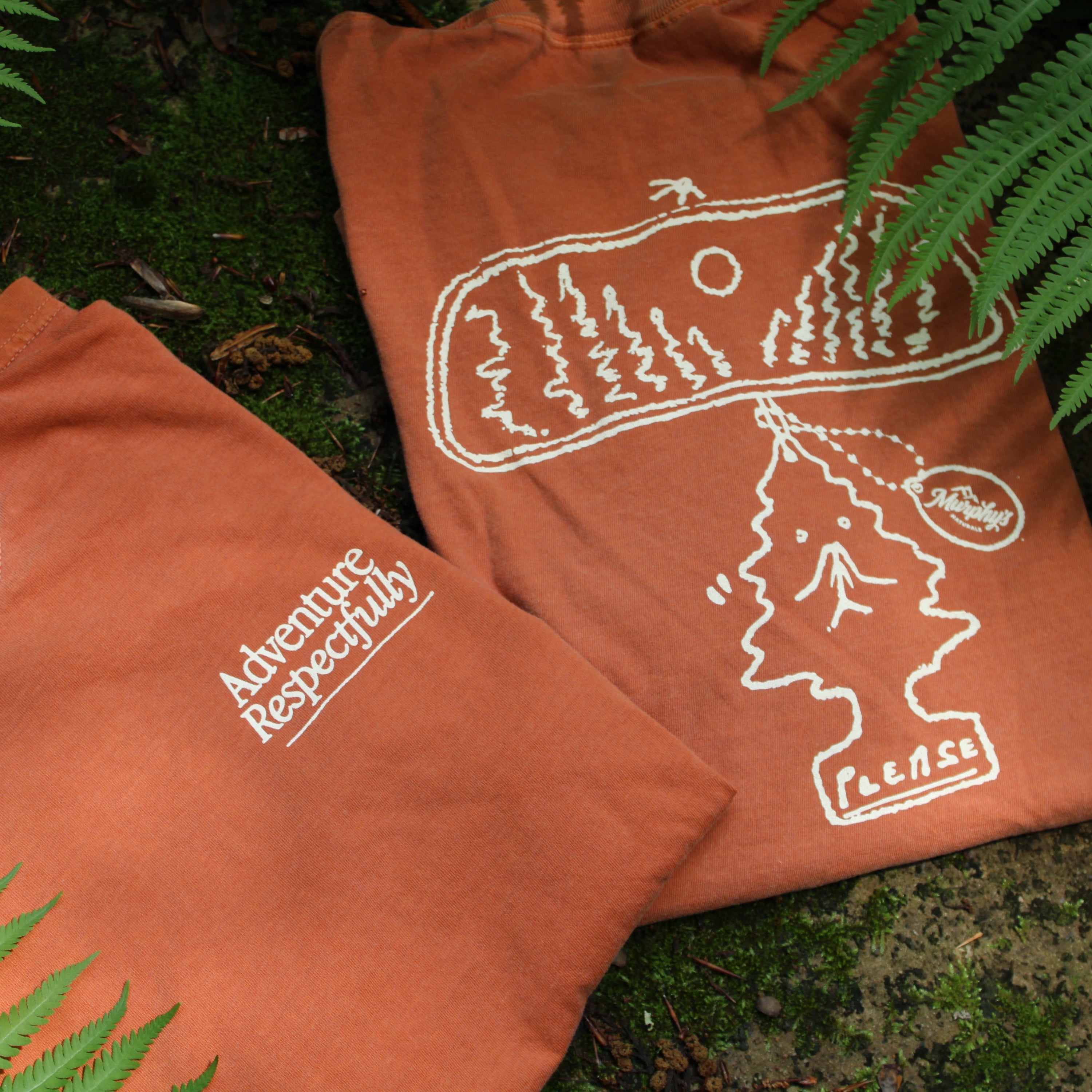 Adventure respectfully front and back of  t shirt shown folded on a mossy surface