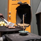 green incense stick holder in front of a grill