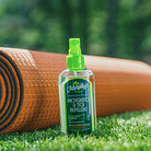 Bottle of Murphy's Mosquito & Tick Repellent on grass with a brown rolled up yoga mat in the background