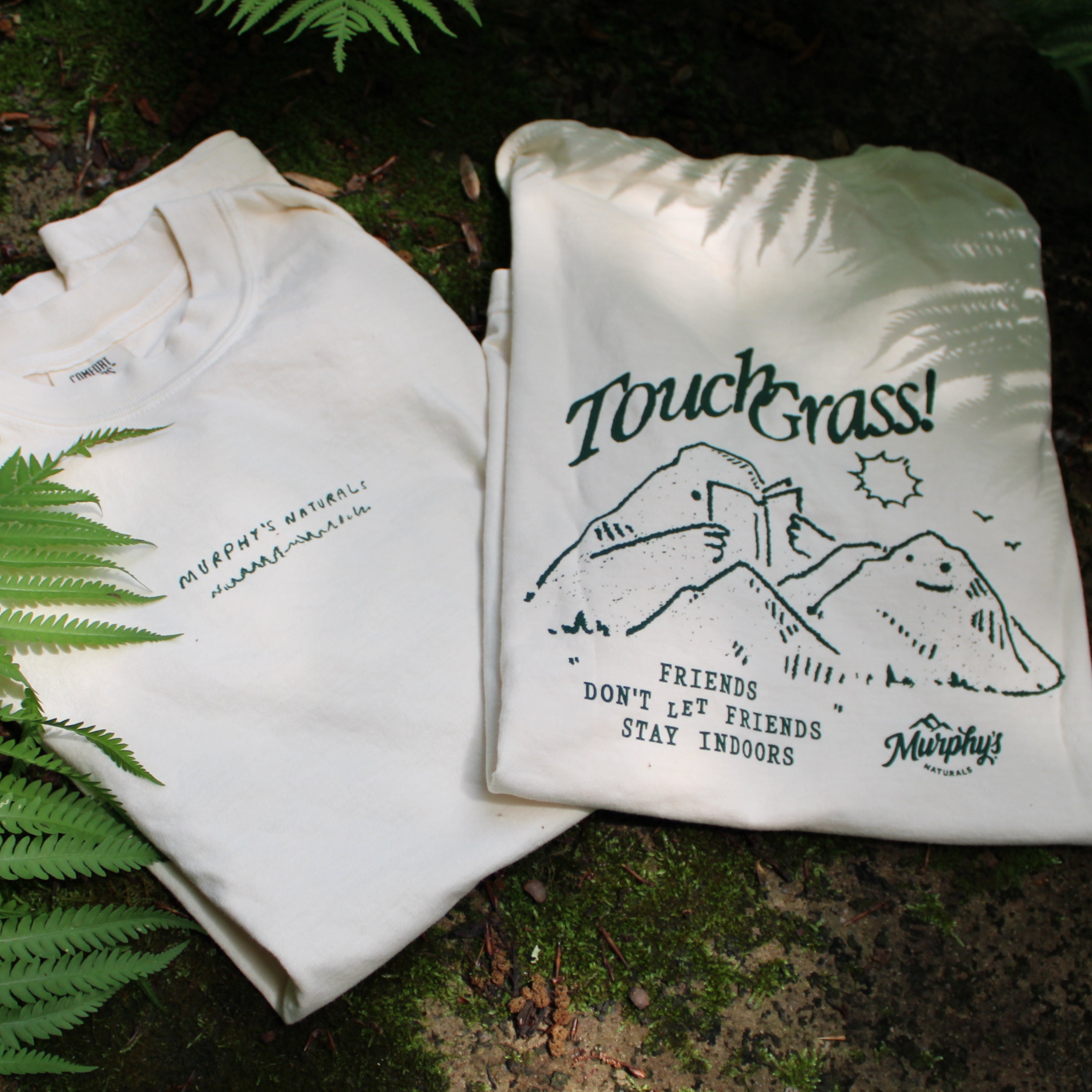 The front and back of the shirt folded on a mossy cement table with ferns poking through