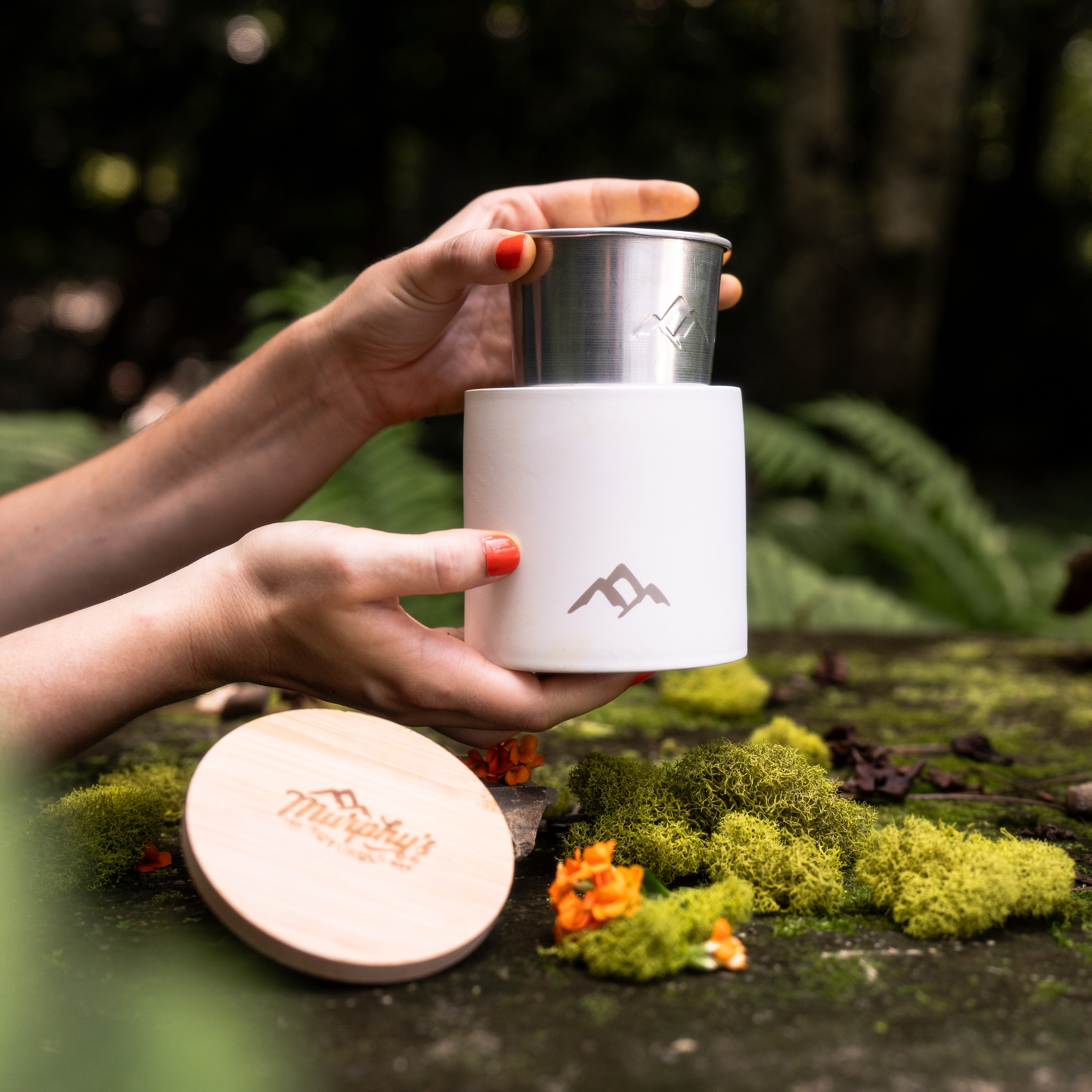 A person holding a white stoneware candle vessel with a lid, designed for mosquito repellent.
