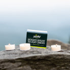mosquito repellent tea light candle carton on top of a rock with 3 tealights lit