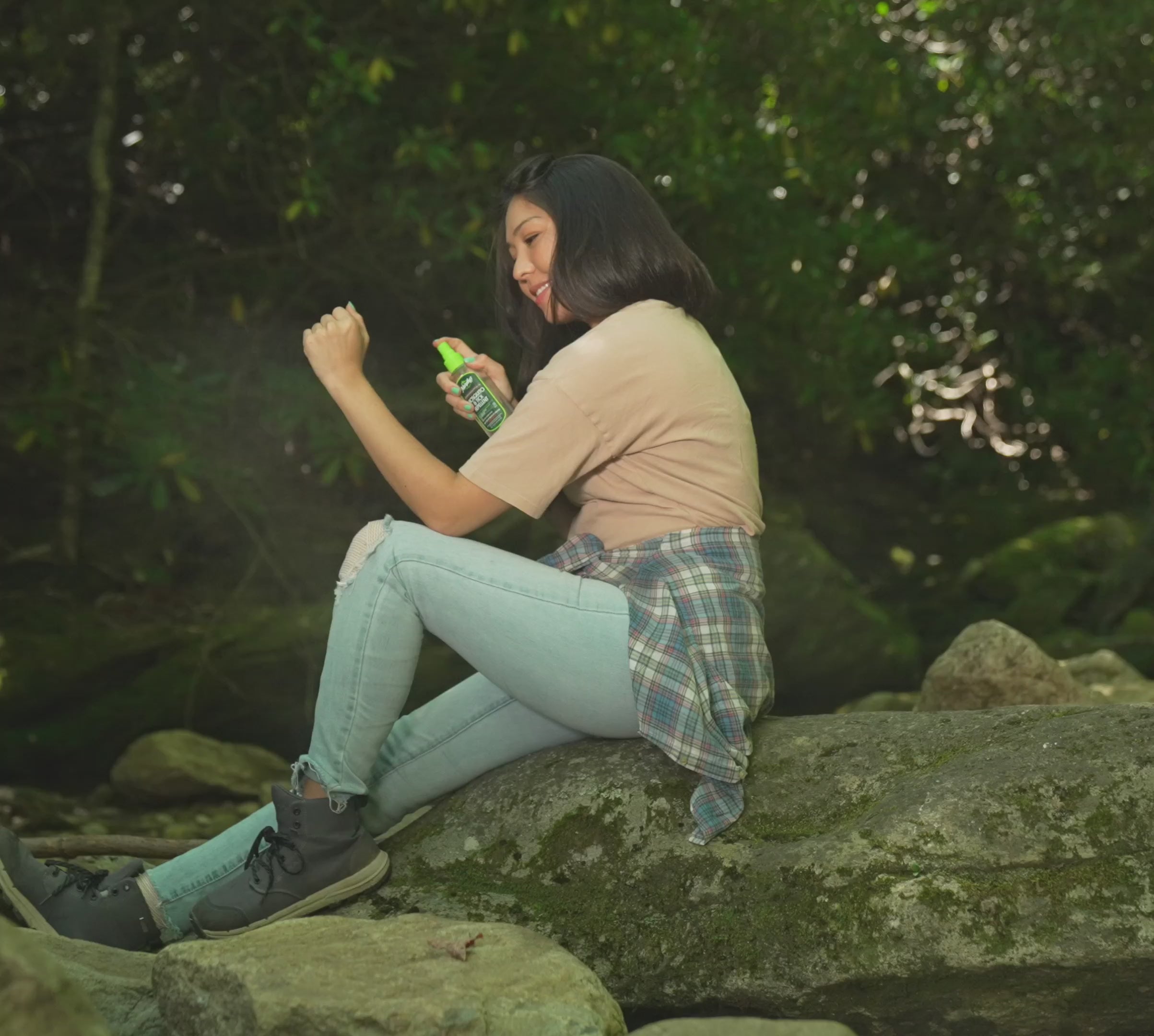 Womanand man  sitting on river rocks spraying Murphy's Naturals Lemon Eucalyptus Oil Spray on their arms.