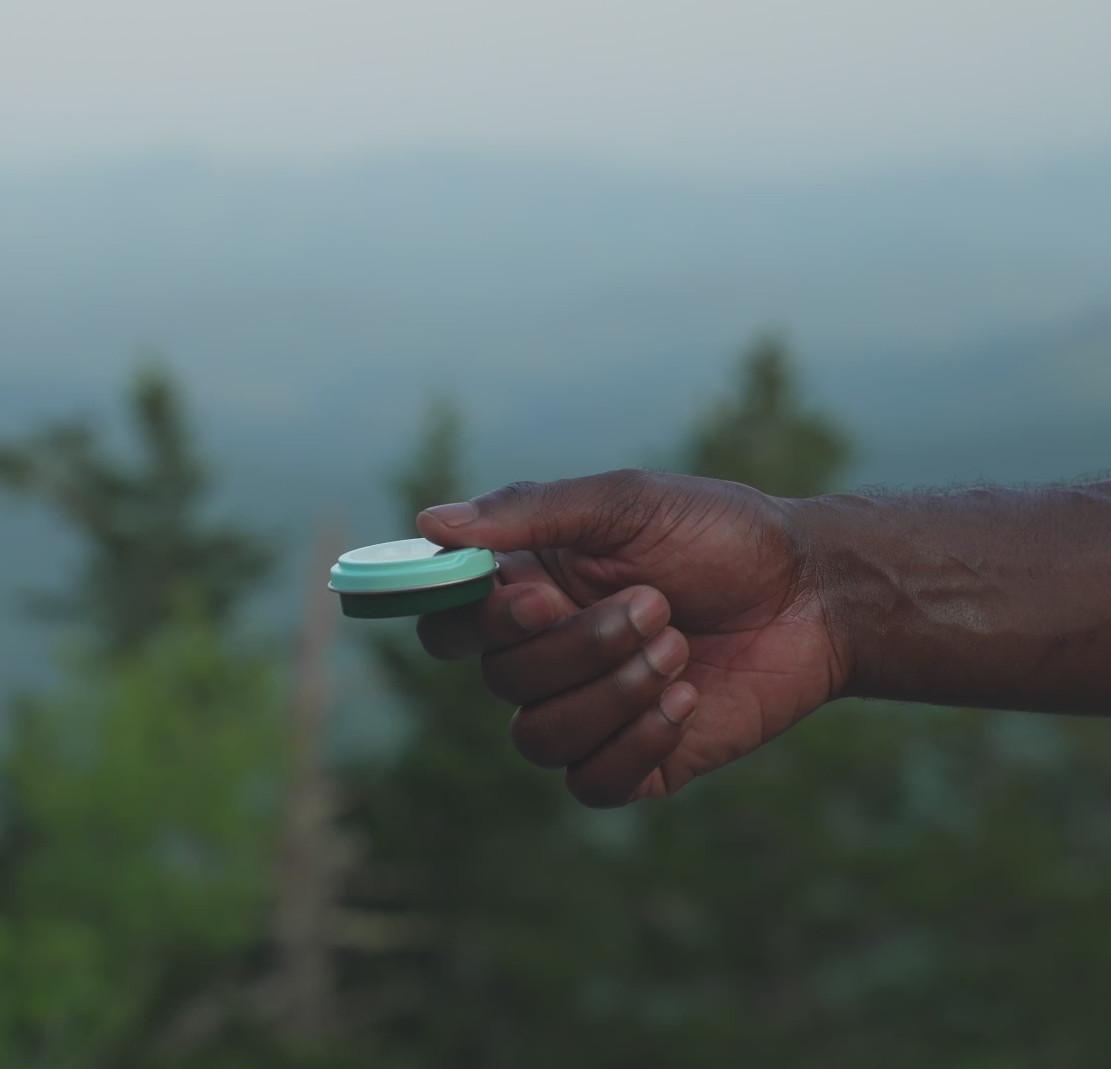 Bite relief balm tin being applied to skin