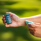 Person applying a product to their wrist with a green blurred background