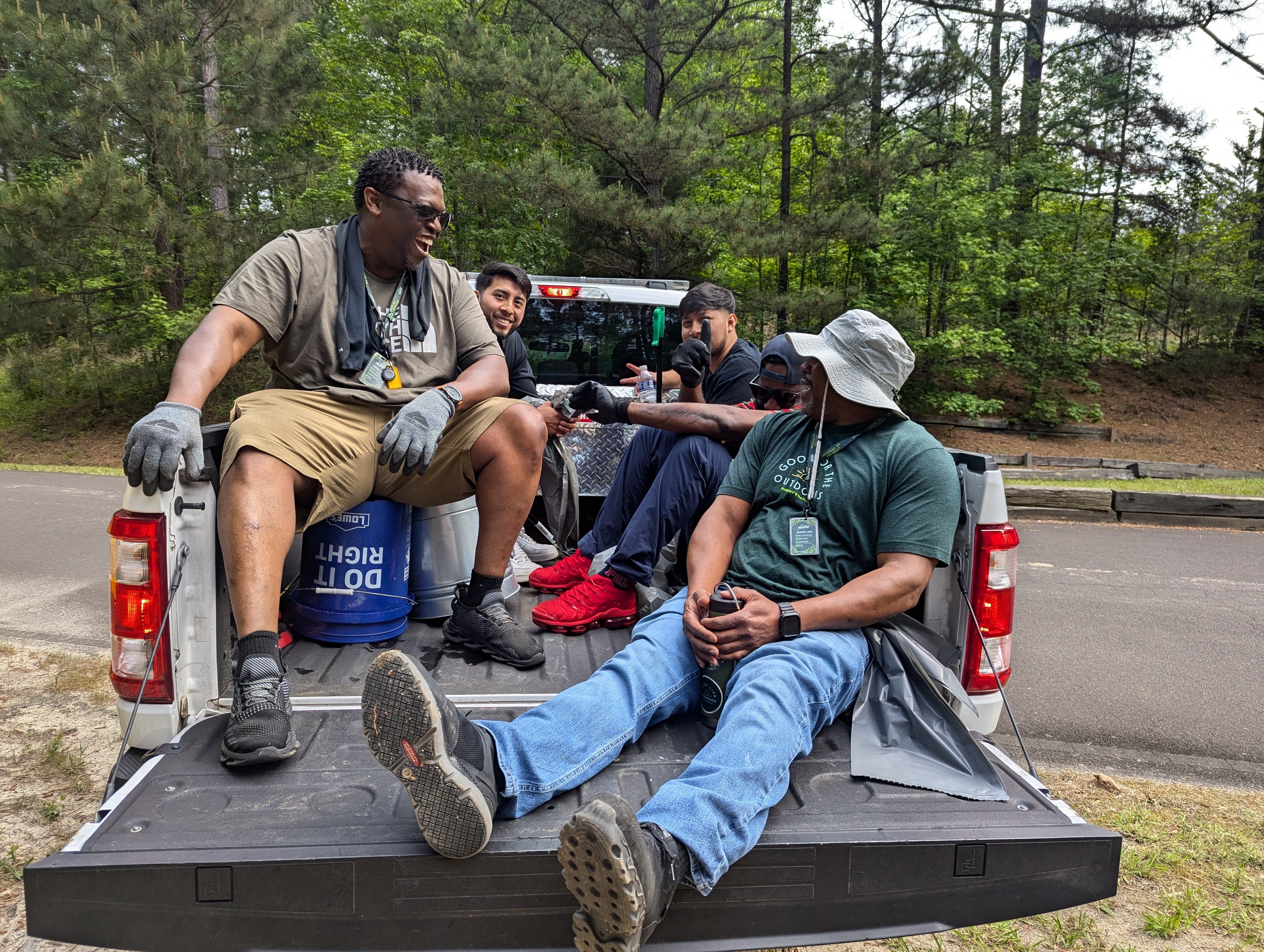 Four men (Murphy's Employees) sitting in the back of a pickup truck with a forest in the background
